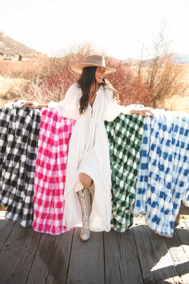 Young woman standing in front of four different colored gingham check blankets.
