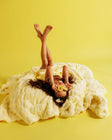 Person lying on a yellow blanket with a yellow background.