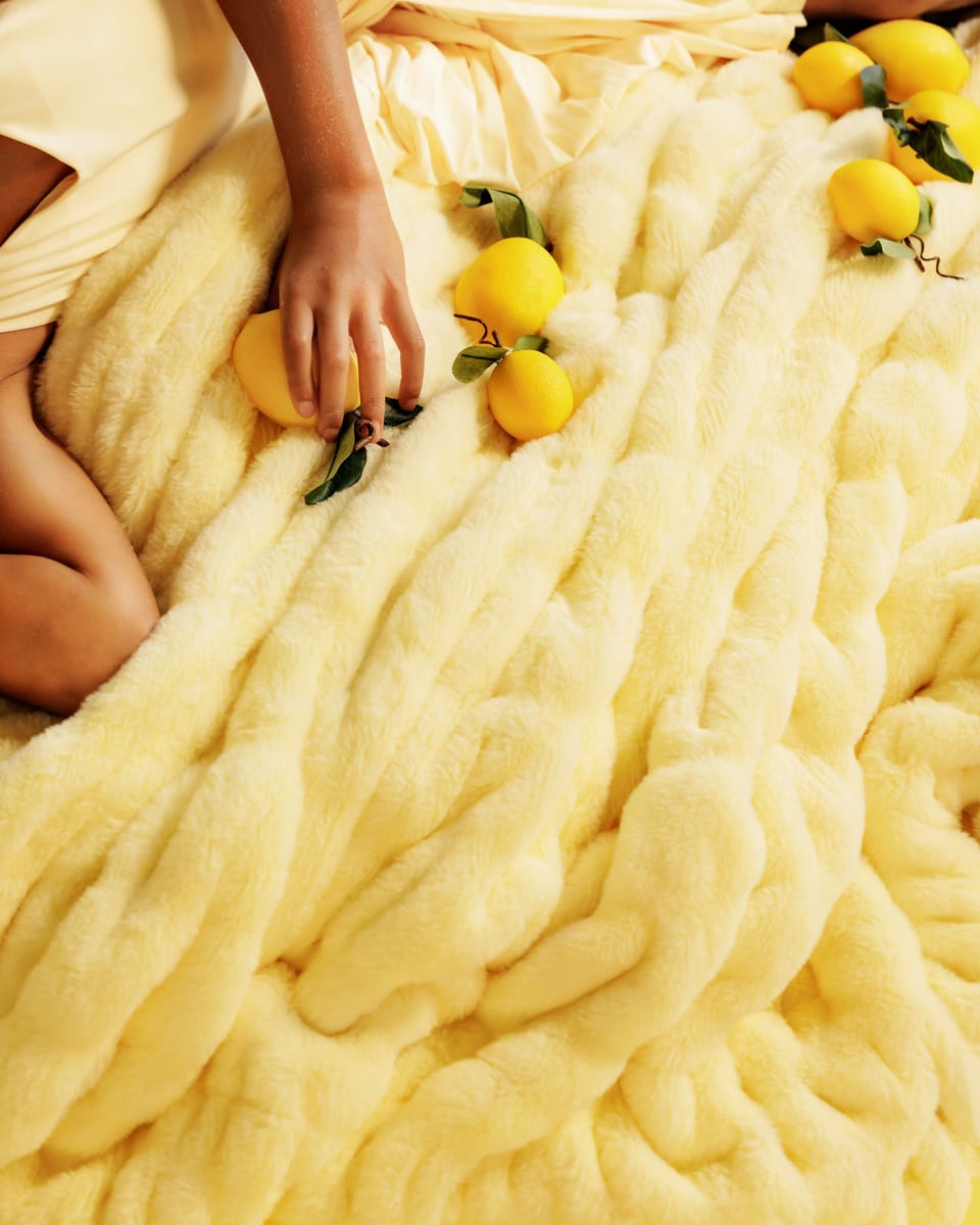 Person holding lemons on a fluffy yellow blanket