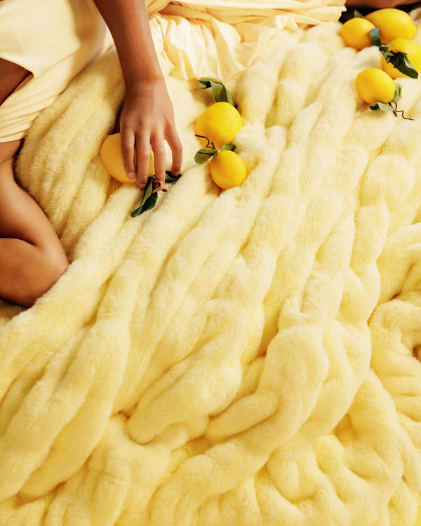 Person holding lemons on a fluffy yellow blanket