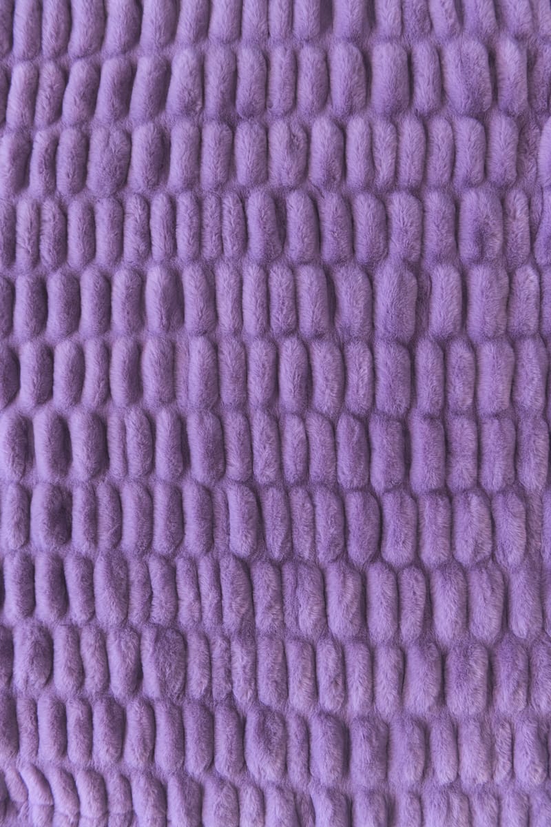 A close-up of a textured purple stretchy blanket.