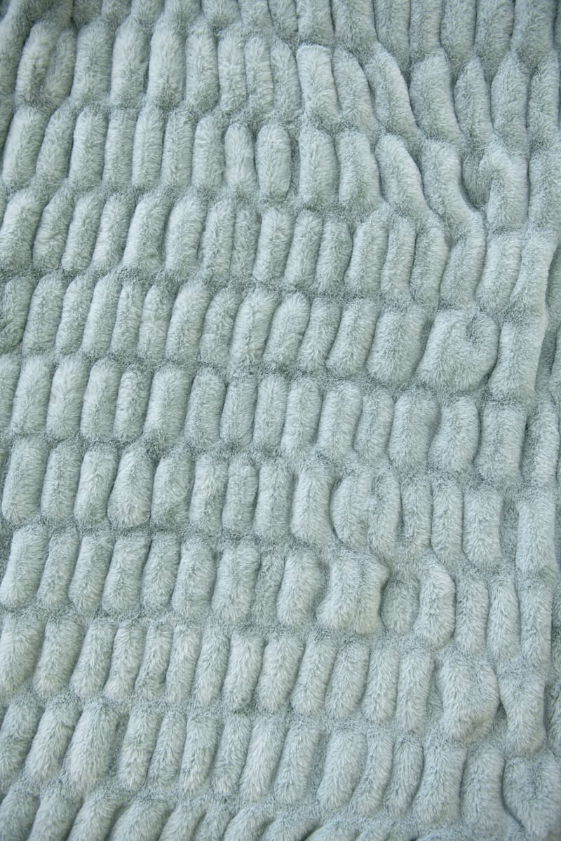Close-up of textured light blue fabric with a wavy pattern from the Hugs Willow Blue Blanket.