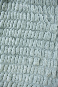 Close-up of textured light blue fabric with a wavy pattern from the Hugs Willow Blue Blanket.