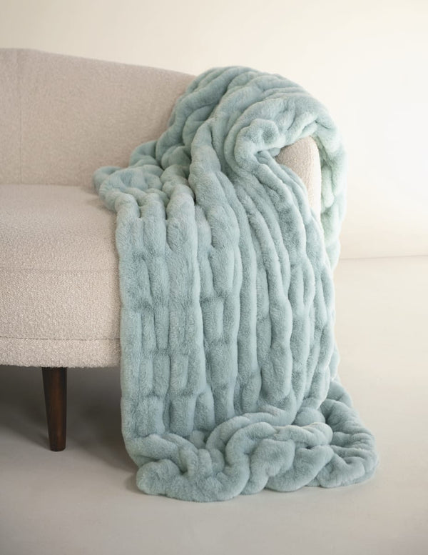 Light willow blue textured throw blanket draped over a beige sofa.