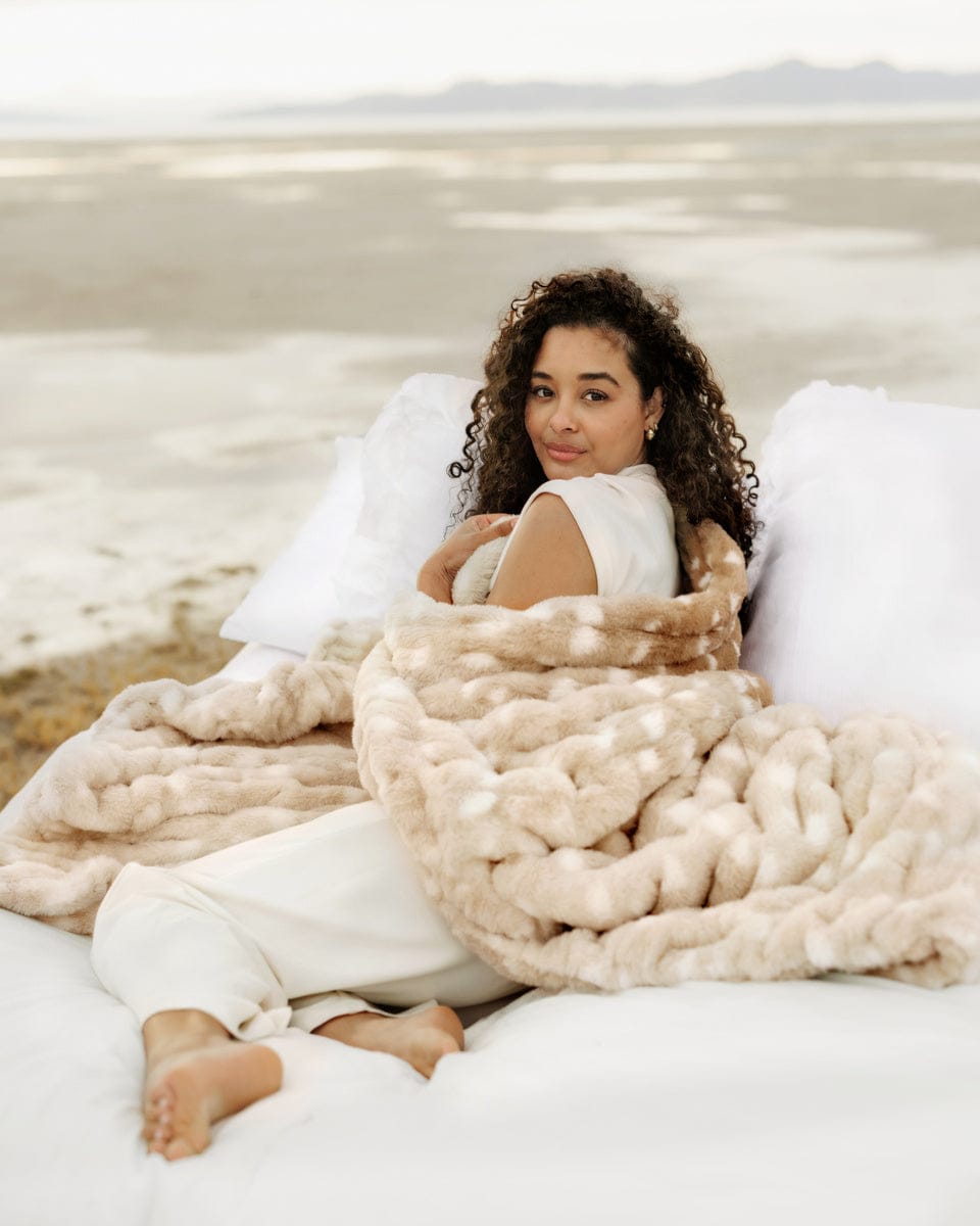 A woman wrapped in a Hugs Antelope Blanket, showcasing its plush and cozy design outdoors.