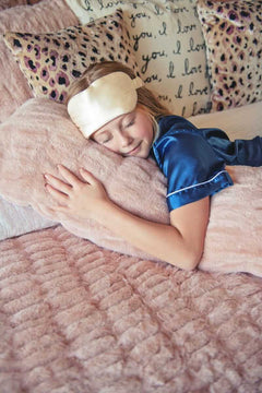 Child resting on a plush Hugs Blush Sham pillow and bedding.