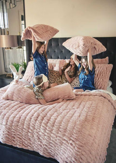 Four girls playing on a bed with plush Minky Couture Hugs Blush Sham bedding and pillows.