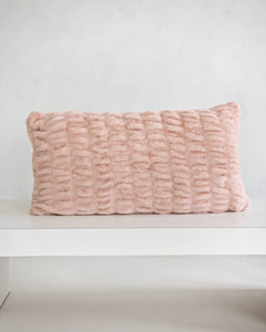 Hugs Blush Sham on a white table, showcasing its soft texture and cozy blush pink color.