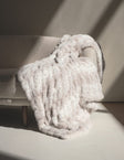 Hugs Cream Fawn Blanket draped on a cozy couch, showcasing its plush texture and subtle fawn print.