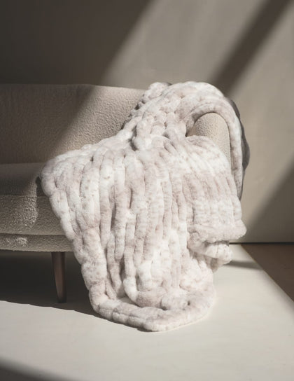 Hugs Cream Fawn Blanket draped on a cozy couch, showcasing its plush texture and subtle fawn print.