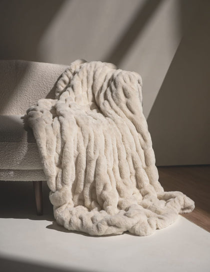 Hugs Creme Brulee Blanket draped over a cozy chair, showcasing its rich, velvety texture and luxurious softness.