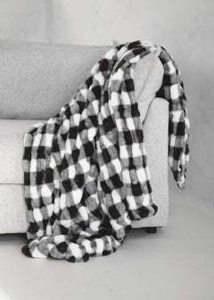 Hugs Gingham Charcoal Blanket draped over a gray couch, featuring a cozy black and white gingham pattern.