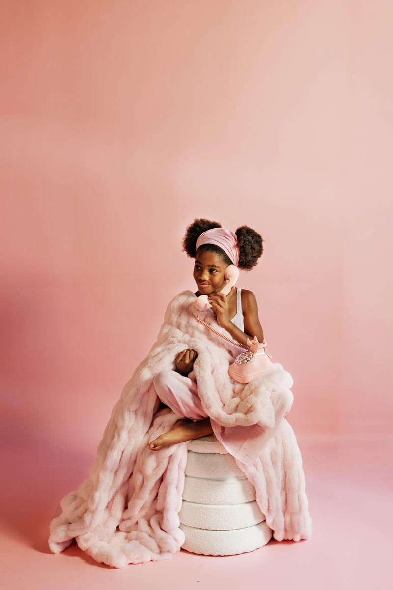 Young girl wrapped in a light pink blanket with a making pink background