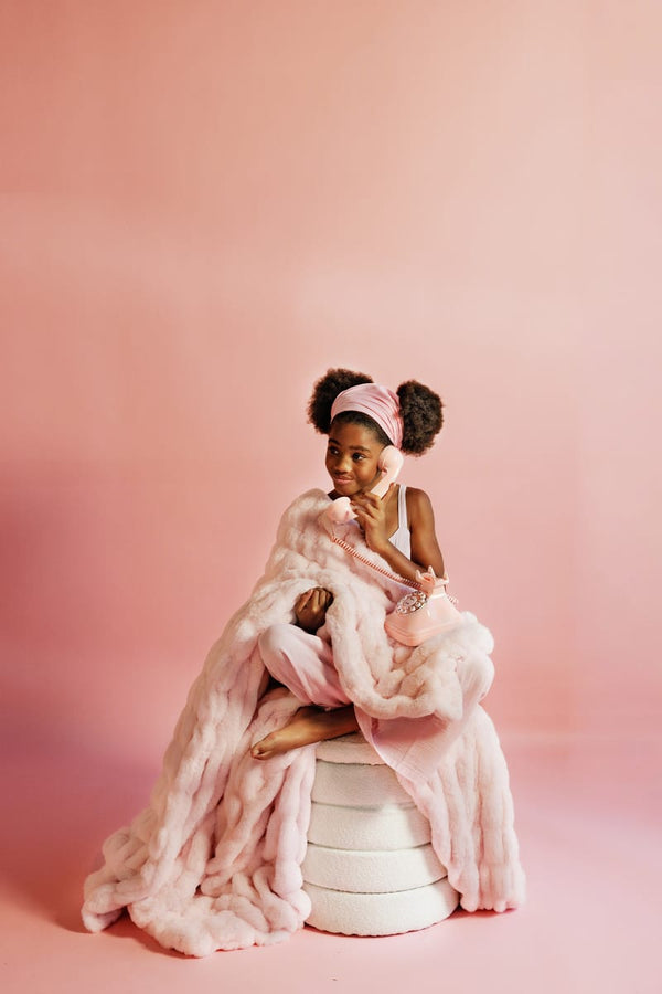 Young girl wrapped in a light pink blanket with a making pink background