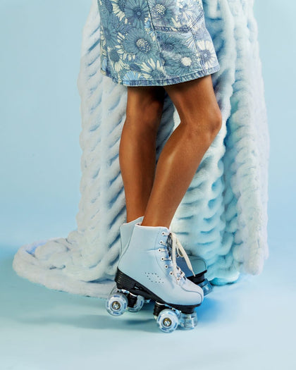 Person wearing light blue roller skates while holding a light blue blanket.