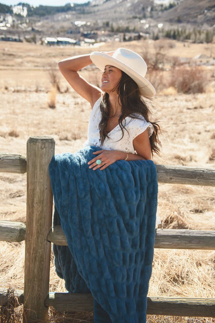 Woman outdoors wearing a Hugs Midnight Blue Blanket, enjoying warm comfort in a stylish setting.