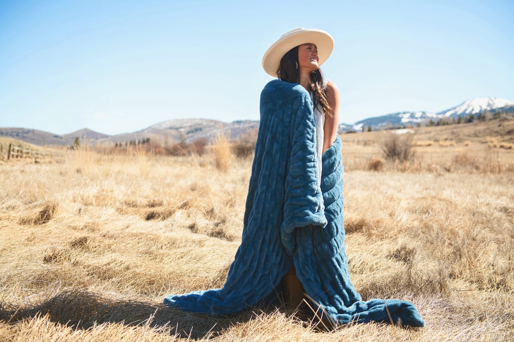 Woman wearing the Hugs Midnight Blue Blanket outdoors, showcasing its cozy material in a picturesque landscape.