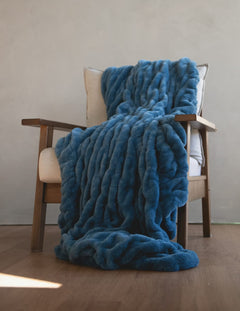 Hugs Midnight Blue Blanket draped over a cozy chair, showcasing its soft texture and rich blue color for ultimate comfort.