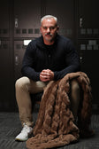 Man sitting on the floor with a Minky Couture Hugs Milk Chocolate blanket in front of lockers