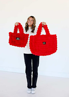 A model showcasing the Annie Bag Ripple Red in small and large sizes, highlighting its luxurious style and texture.
