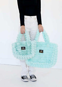Woman holding two Annie Bag Ripple Tiffany in soft aqua colors, showcasing luxury and style.
