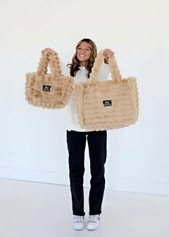 A woman showcasing two sizes of the Annie Bag Ripple Ecru, a luxurious and stylish accessory.