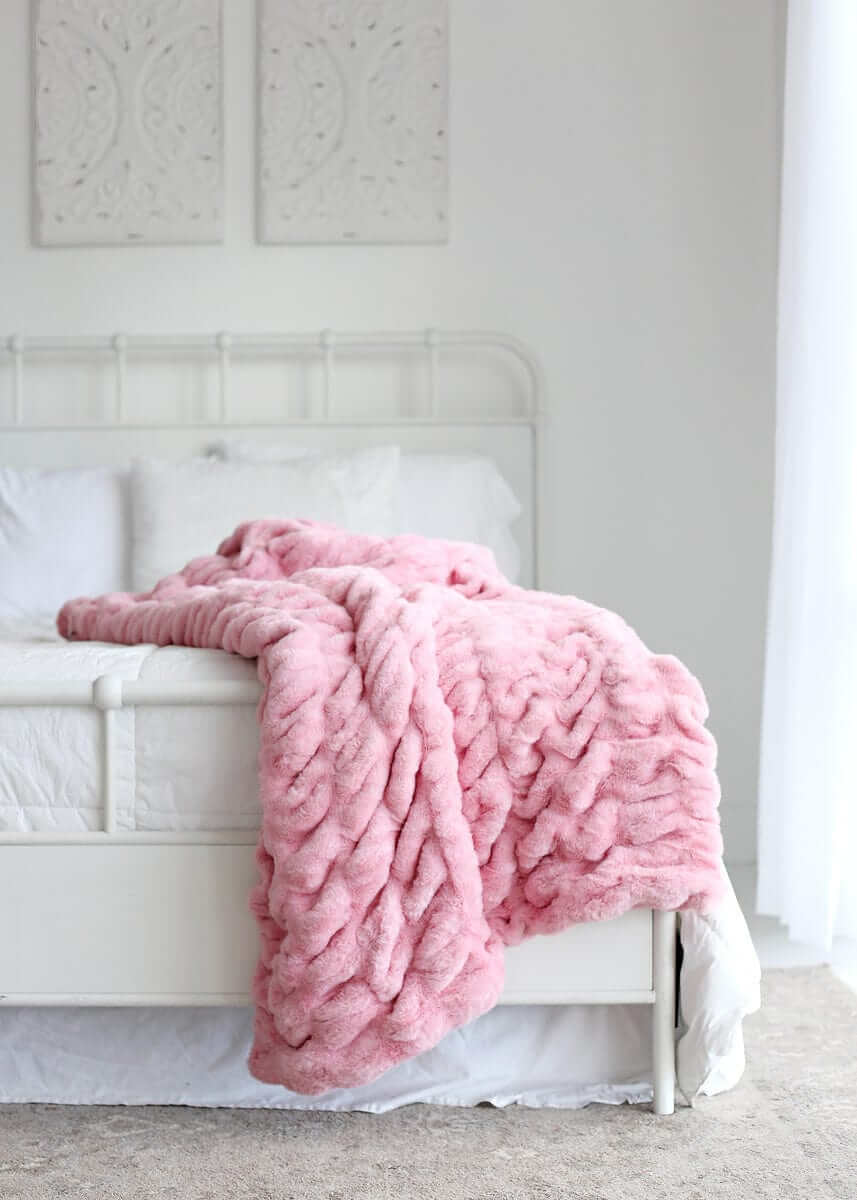 Hugs Cookie Pink Blanket draped over a bed, showcasing its soft texture and cozy design.