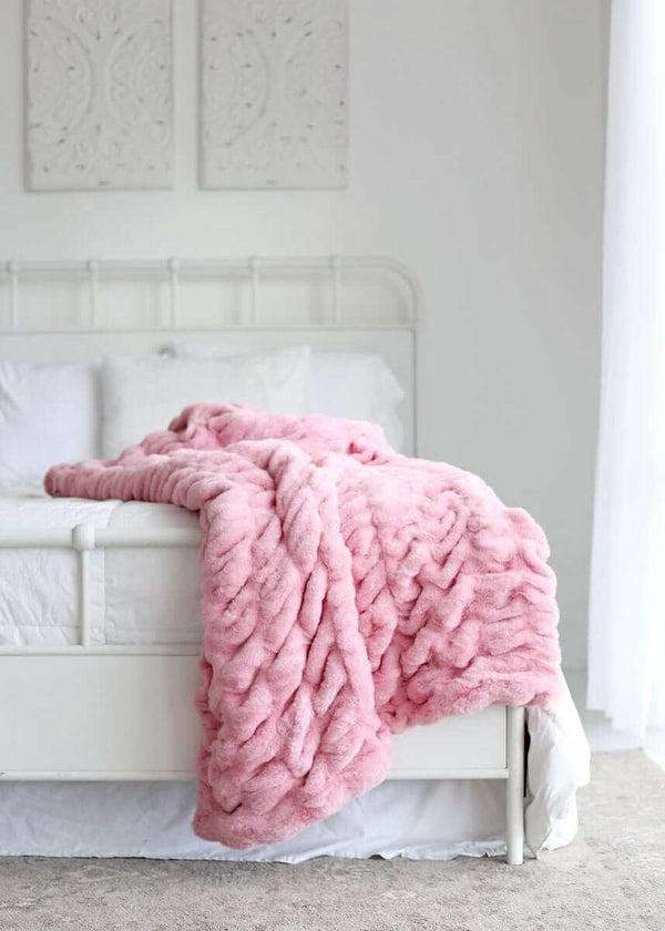 Hugs Cookie Pink Blanket draped over a bed, showcasing its soft texture and cozy design.