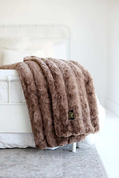Ultra Sorbet Gingersnap Blanket displayed on a bed, showcasing its faux fur texture and cozy light brown color.