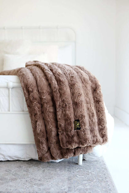 Ultra Sorbet Gingersnap Blanket displayed on a bed, showcasing its faux fur texture and cozy light brown color.