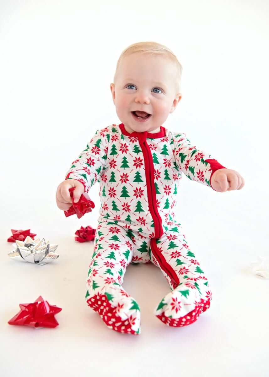 Infant Unisex Zipper Footie with Poinsettia and Tree worn by a baby, surrounded by festive decorations.