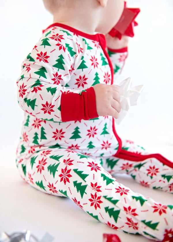Infant Unisex Zipper Footie on a baby, showcasing festive holiday design with trees and poinsettias.