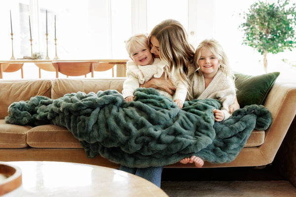 Lindsay Arnold cuddling children under a green Minky Couture blanket