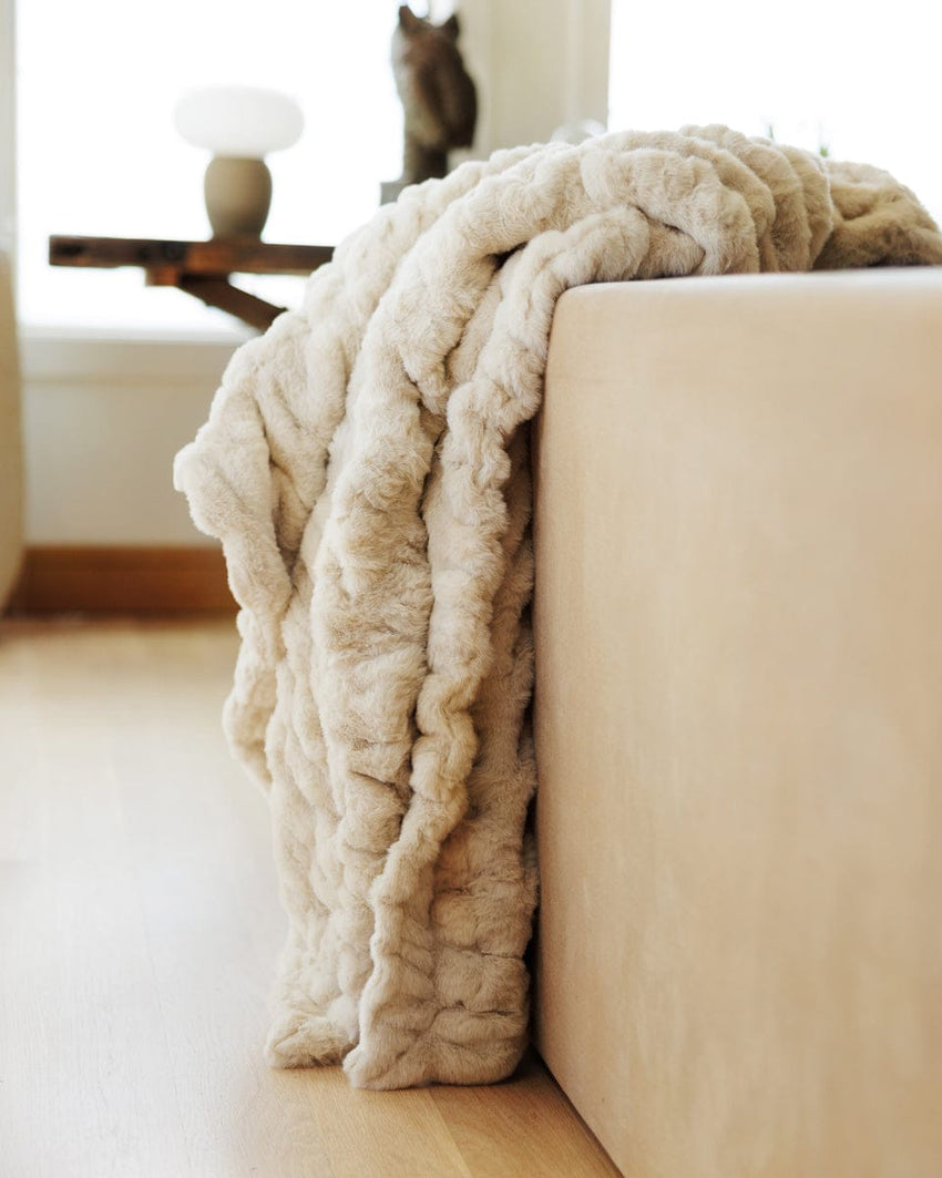 Cream Minky Couture blanket draped over the side of a tan couch