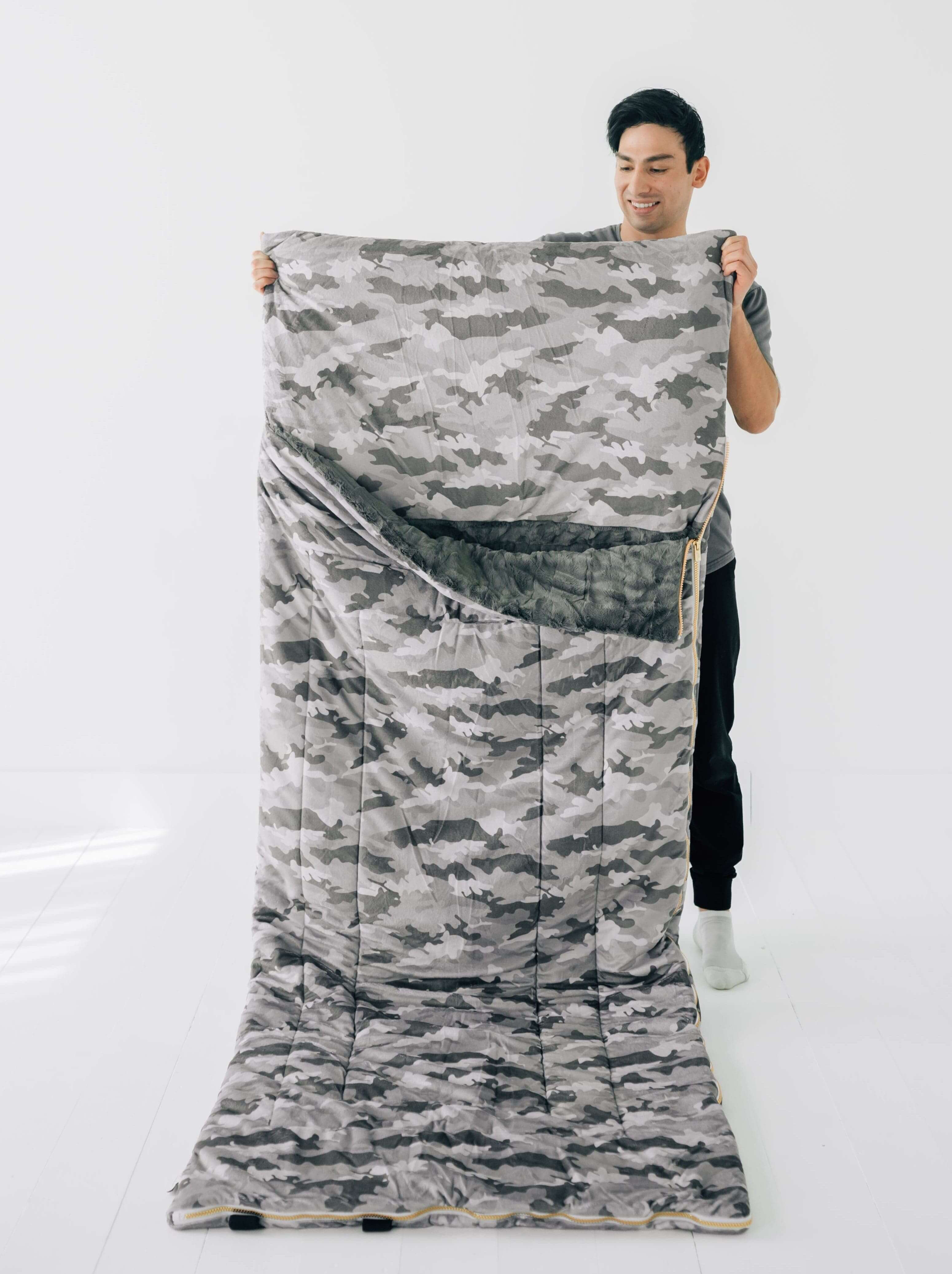 Camo Sleeping Bag being held by a person, showcasing its camo design and cozy features.