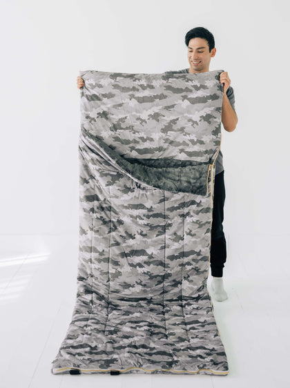 Camo Sleeping Bag being held by a person, showcasing its camo design and cozy features.