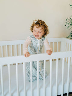 Dainty Floral Sage Wearable Minky Blanket on a happy toddler in a crib, showcasing safe sleep for infants.