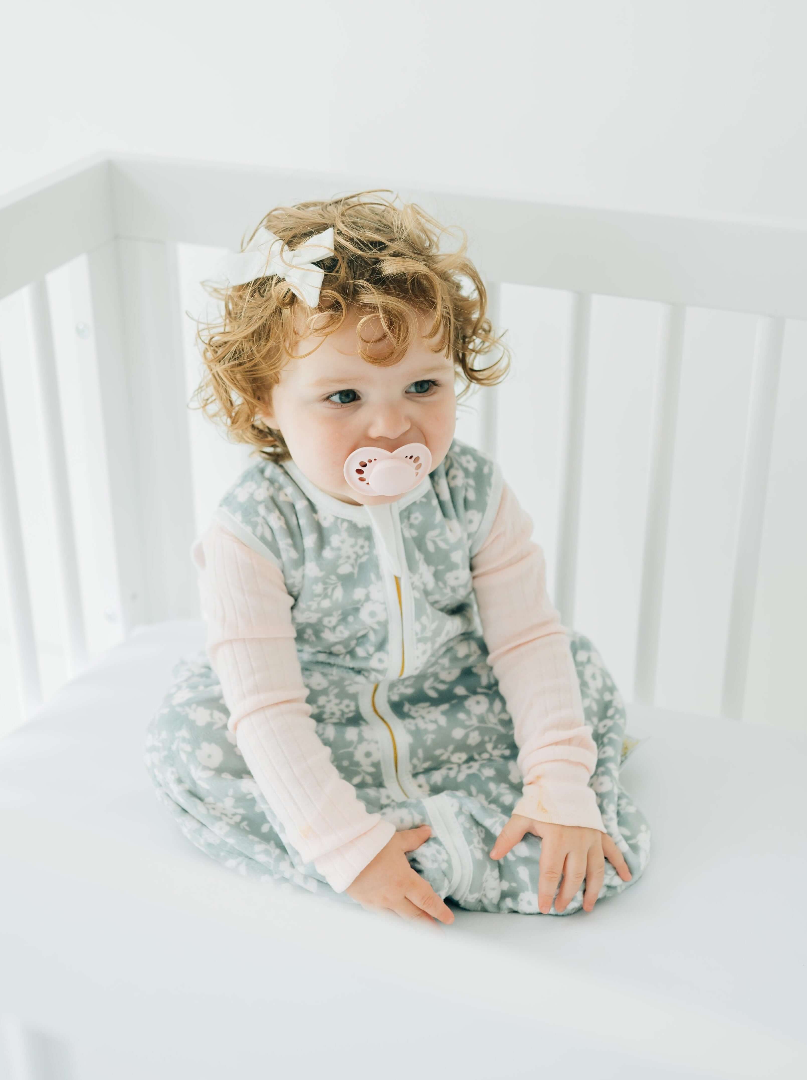 Dainty Floral Sage Wearable Minky Blanket on a baby sitting in a crib, enjoying cozy comfort.