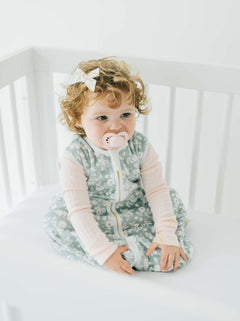 Dainty Floral Sage Wearable Minky Blanket on a baby sitting in a crib, enjoying cozy comfort.