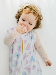 A baby in a Butterfly Wearable Minky Blanket, enjoying comfort while using a pacifier.