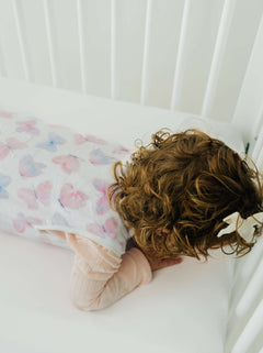 A cozy baby sleeping peacefully in a Butterfly Wearable Minky Blanket in a crib.
