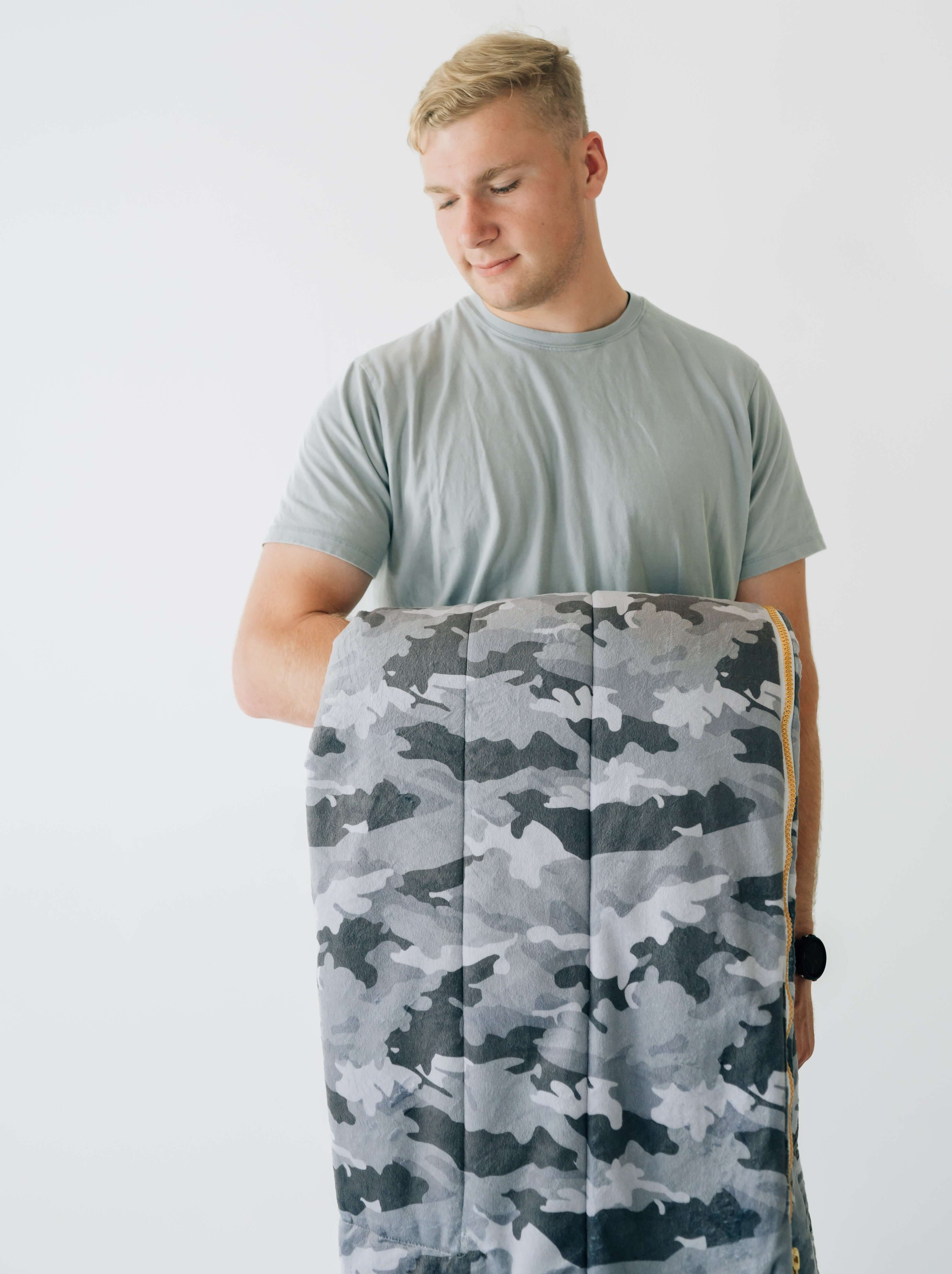 Sleeping Bag Camo held by a young person, showcasing its stylish camouflage design and plush lining.