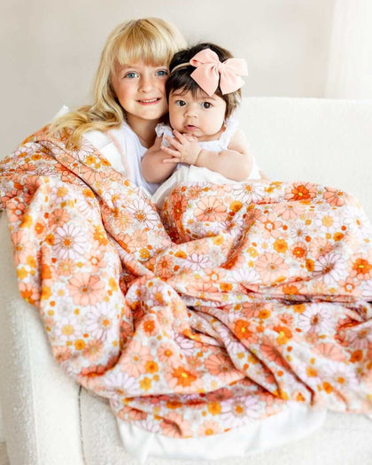 Boho Floral Blanket featuring girls snuggled under a colorful flower design with peach minky backing.
