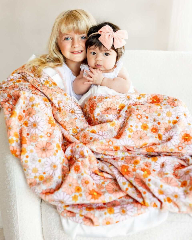 Boho Floral Blanket featuring girls snuggled under a colorful flower design with peach minky backing.