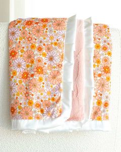 Boho Floral Blanket featuring vibrant orange, pink, yellow flowers with plush peach backing and white satin ruffle.