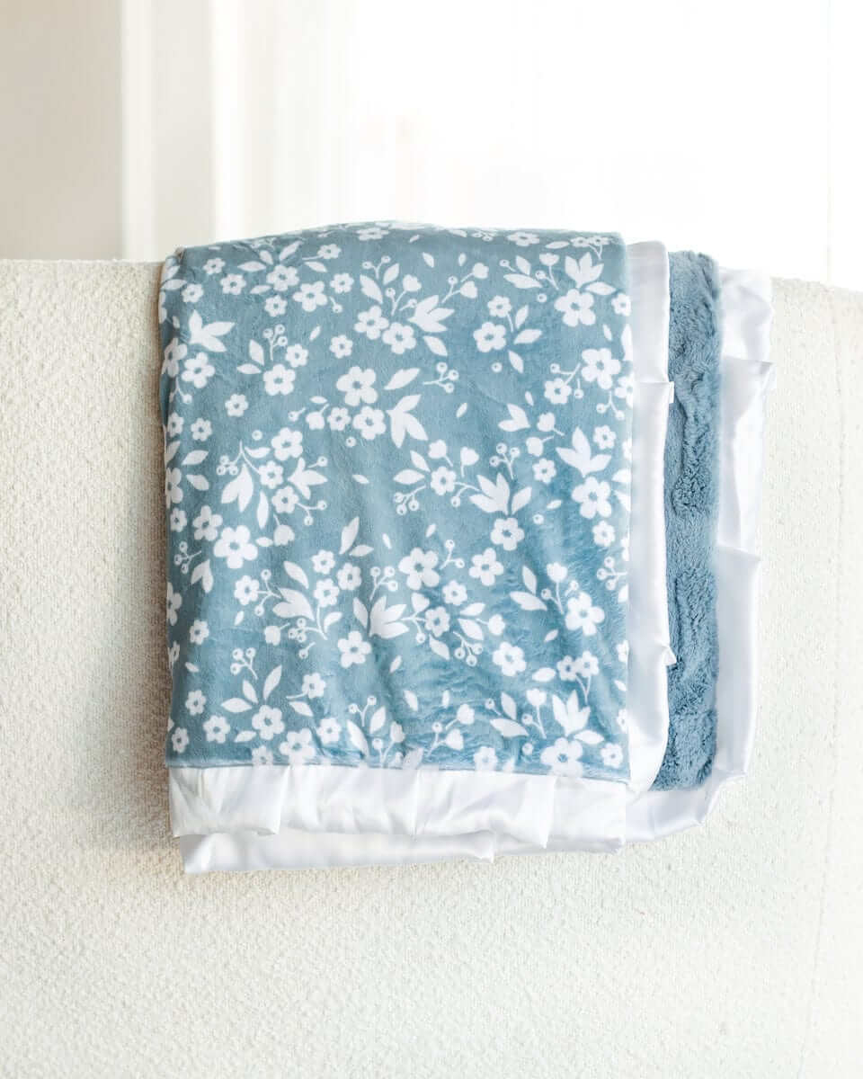 Dainty Floral Blue Blanket with small white flowers and leaves on a light blue background and plush minky backing.