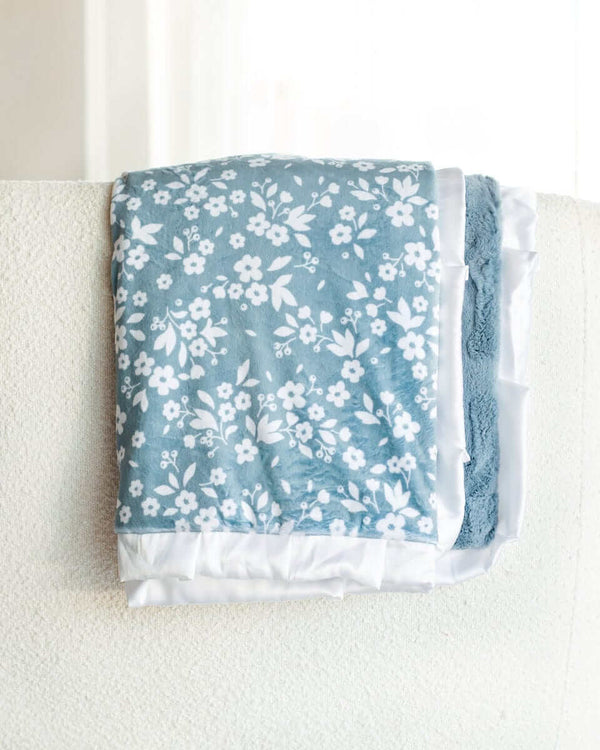 Dainty Floral Blue Blanket with small white flowers and leaves on a light blue background and plush minky backing.
