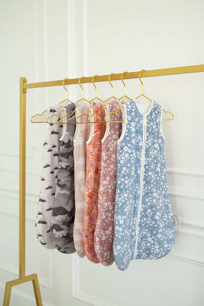 Wearable Minky Blanket collection displayed on gold hanger with floral and camo patterns for infants.