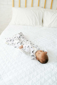 Infant peacefully sleeping in Mountains Wearable Minky Blanket on a cozy white bed.