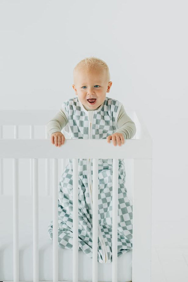 Sage Check Wearable Minky Blanket on a baby in crib, featuring an imperfect check pattern and gold zipper.